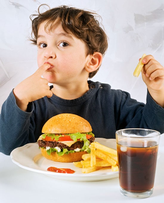 Kind aan tafel met een hamburger en friet